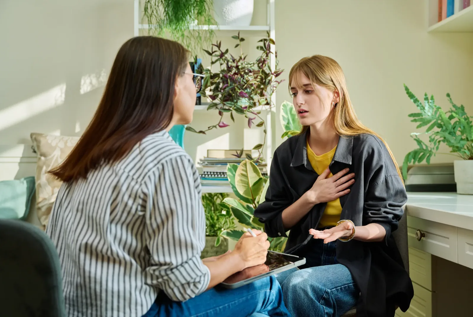 Two people in a warm, attentive conversation, one listening while the other speaks about how she is feeling